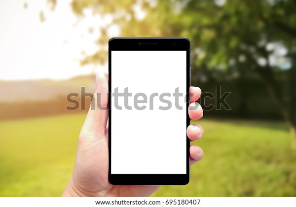 left hand using smartphone\
with blank screen on outdoor car parking at night blur background,\
blur car parking background, outdoor car parking blurred\
background