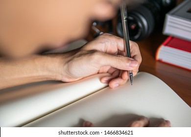 Left handed man writing on notebook