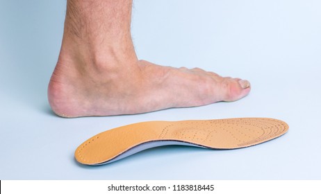 The left leg of an adult male with signs of foot disease next to the orthopedic insole. Means for the treatment of flat feet.