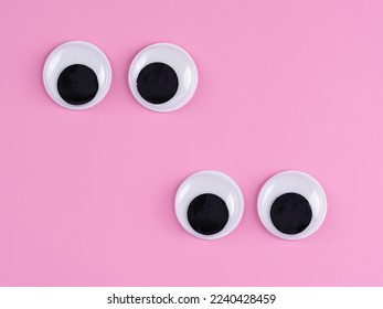 left offset pairs of  googly eyes funny Isolated on bright pink background copy space logo