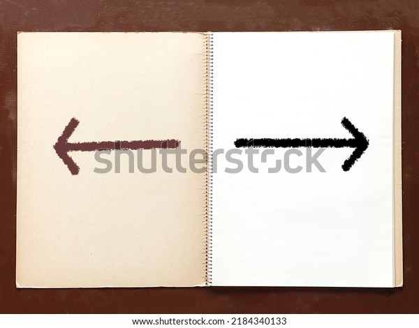 Left and right arrows on an open old sketchbook on\
a desk.