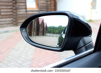 Left side rear-view mirror on a modern car. View from inside the car. Rear view mirror with reflection.