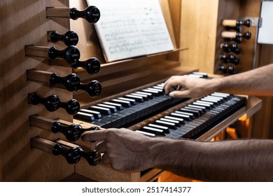 Left side view of organist playing the organ and changing the organ registers with his left hand in the Catholic Church. - Powered by Shutterstock