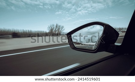 Left side window view scene of a road car on a highway on a beautiful forest landscape with sharp backward mirror
