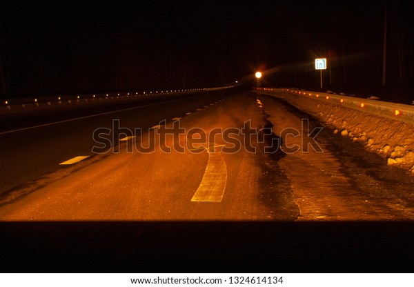 Left turn. Part of the road in front of the\
car at night. Turn indicator on\
asphalt.