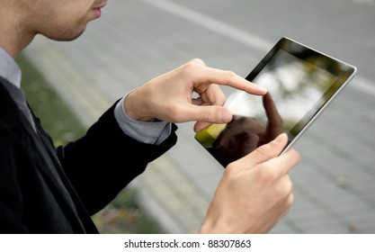 Left-handed businessman holding and touching on digital tablet pc at the park. - Powered by Shutterstock