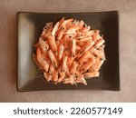 Leftover boiled shrimp in a white plate on grey background. Waste food shrimp peeled, detail of the heads and eyes of this seafood. Peeled skin and head for making a delicious broth shrimp.