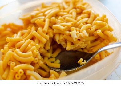 Leftover Bright Orange Kraft Dinner Macaroni And Cheese Being Spooned For Reheating