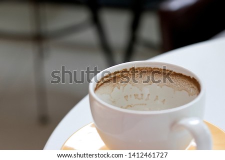 Leftover coffee in white cup on table.