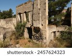 Leftover exterior wall of one of the houses in the abandoned village of Kayaköy with chimney, windows and garden, near Fethiye, Turkey