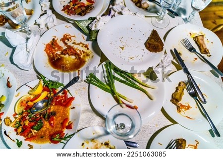The leftover food and dirty dishes on the restaurant table. Scraps left over after the party.