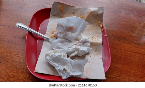 Leftover Food On A Red Plastic Plate On Wooden Table