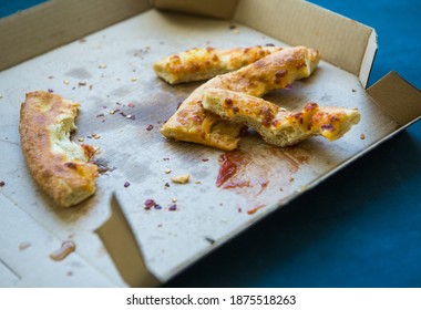 Leftover Pieces Of Pizza Crust Laying On The Pizza Box Carton. Fast Food Garbage In The Food Court.