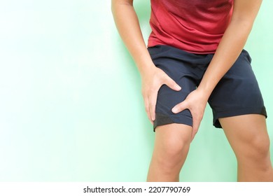 Leg Cramps, Pain And Injury Concept. Young Asian Athlete Man In Running Clothes Holding His Thigh Muscle With Copy Space.