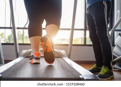 leg of fat woman being run or jog on belt of treadmill machine, workout under intruction of trainer
