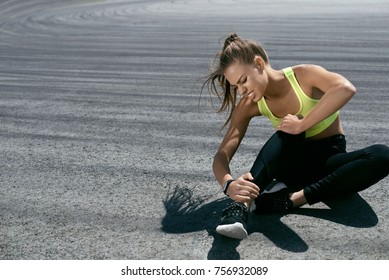Leg Injury. Woman Suffering From Pain In Leg After Workout. Beautiful Girl In Sportswear Sitting And Touching Painful Ankle Injured While Training Outdoors. Sports Injury. High Resolution