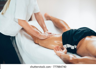 Leg massage. Physical therapyst massaging leg of young male athelete - Powered by Shutterstock