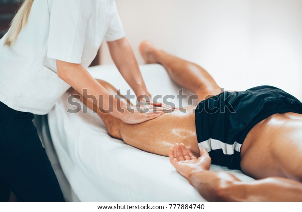 Leg massage. Physical therapyst massaging leg of\
young male athelete
