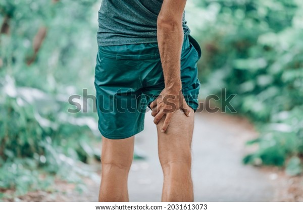 Leg\
muscle pain sports injury runner man touching painful hamstring\
muscle. Legs physiotherapy care athlete massaging sore muscles\
during running training in summer park\
outside.