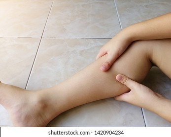 Leg pain or calf muscle in a girl on white tile floor background, health care concept 