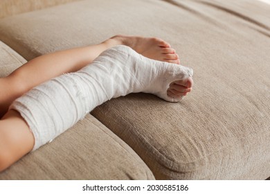 Leg In Plaster Of A Teenage Girl On A Sofa After An Accidental Fall With An Ankle Fracture