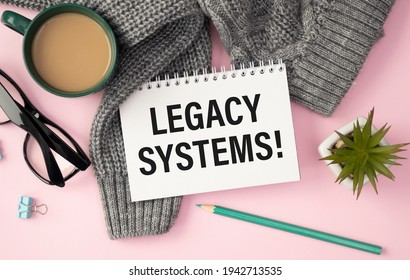 LEGACY SYSTEMS is written in a white notepad near a calculator, coffee, glasses and a pen. Business concept