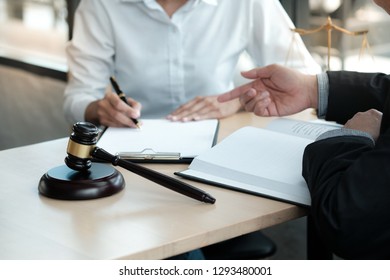 Legal counsel presents to the client a signed contract with gavel and legal law. justice and lawyer concept - Shutterstock ID 1293480001