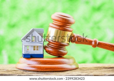 Legal issues in real estate transactions. A small model house and a judge's gavel placed near each other. The intersection of law and real estate in various aspect e.g property rights, contracts, etc