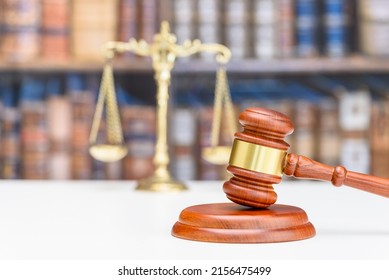 Legal office of lawyers, justice and law concept : Judge gavel or a hammer and a base used by a judge person on a desk in a courtroom with blurred weight scale of justice, bookshelf background behind.