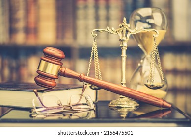 Legal Office Of Lawyers, Justice And Law Concept : Judge Gavel Or A Hammer And A Base Used By A Judge Person On A Desk In A Courtroom With Blurred Weight Scale Of Justice, Bookshelf, Hourglass Behind.