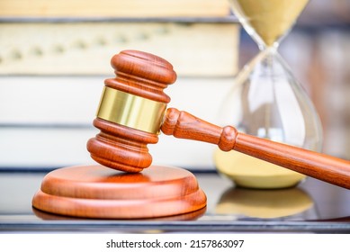 Legal Office Of Lawyers, Justice And Law Concept : Judge Gavel Or A Hammer And A Base Used By A Judge Person On A Desk In A Courtroom With Blurred Books And Bookshelf, A Time Clock Or Hourglass Behind