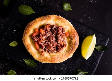 Legitimate Arabic sfiha meat on black cutting board and lemon cut in half on black background - Shutterstock ID 1769570792