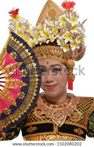 A Legong Dancer Posing at the camera with a fan