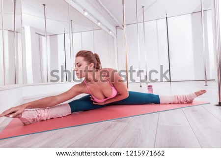 Legs apart. Woman fond of yoga feeling amazing splitting her legs apart while stretching her body
