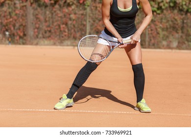 Legs of an athlete girl near a tennis racket