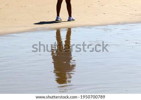 legs of an athlete running barefoot on a sandy beach in sea water.