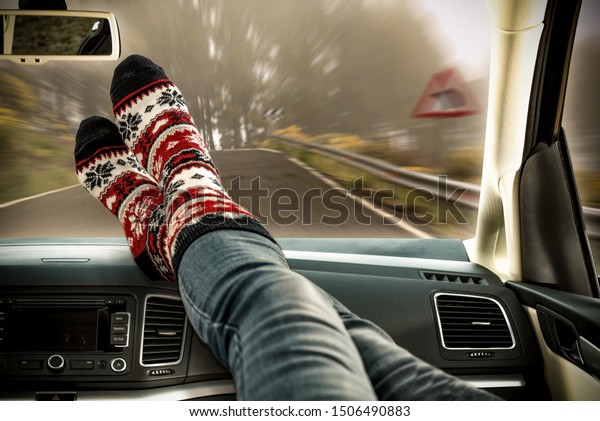 Legs with autumn socks in car and dark
autumn road. Free space for your decoration.

