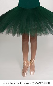 Legs Of Ballerina And A Green Tutu On A White Background