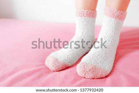 Legs of a beautiful women are wearing warm Socks on bedroom. Fashion pink Socks in cozy background.