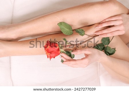 Legs of beautiful young woman after depilation with smooh shiny skin in beauty salon. Womans body wath soft rose. Clear skin, depilation, epilation and health care concepts.
