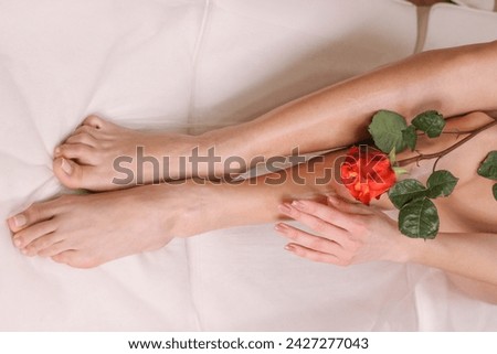 Legs of beautiful young woman after depilation with smooh shiny skin in beauty salon. Womans body wath soft rose. Clear skin, depilation, epilation and health care concepts.