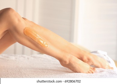 Legs of beautiful young woman with applied sugaring paste in salon. Epilation concept