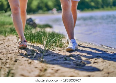 Legs below the knee of a couple in love walking along the sandy shore. Close up.