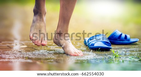  legs of a boy jumping into a puddle of rain without shoes