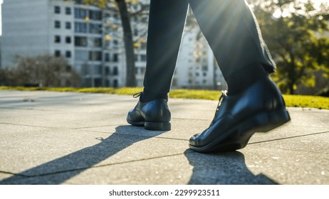 Legs of a businessman in fashionable shoes walking outdoors. Business concept. Close-up view to the businessman in a black new shoes walks on the street. Stylish men wears. Low angle. Rear view. - Powered by Shutterstock