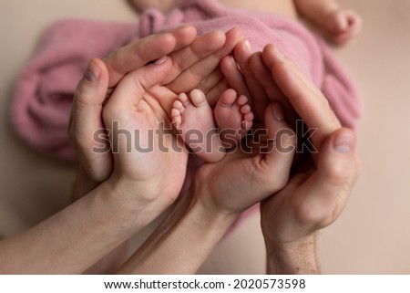 the legs of the child in the arms of the mother and the father, the legs of a newborn baby