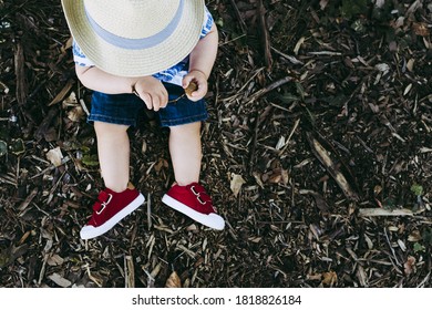 Legs Of Child Sitting In The Grass With Cute Red Sneakers Shoes - Top View