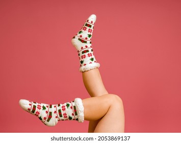 Legs In Christmas Socks Raised Up On Pink Background