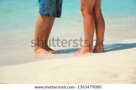 legs of a couple in love on the sand by the sea