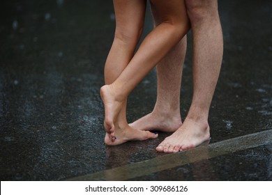 Legs of couple standing on the asphalt road in the rain